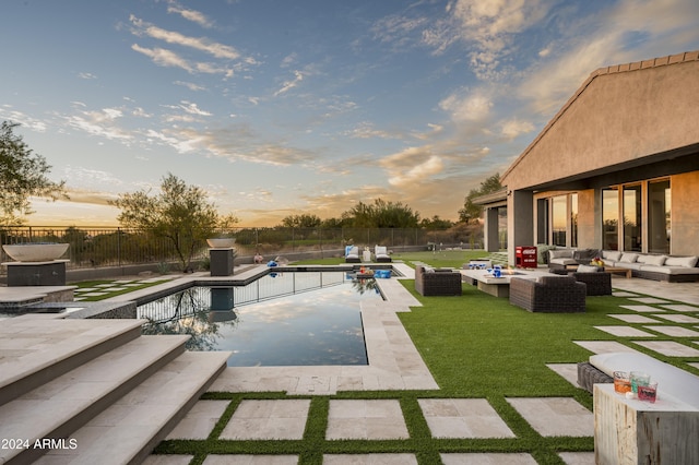 pool at dusk featuring an outdoor hangout area, a patio, and a yard