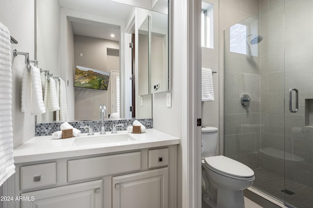 bathroom featuring vanity, toilet, walk in shower, and backsplash