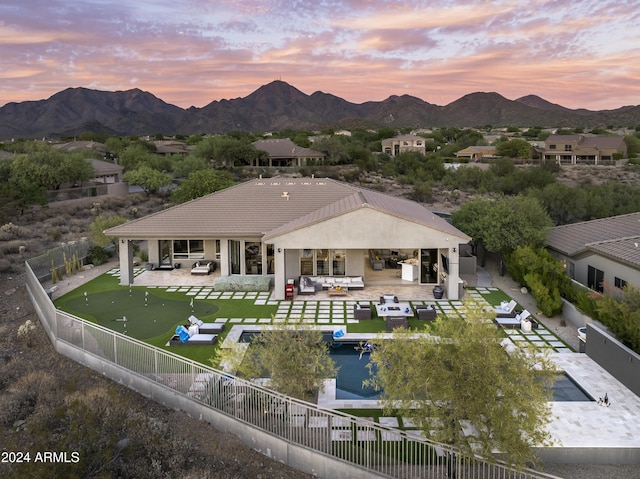 back house at dusk featuring outdoor lounge area, a mountain view, a patio area, and exterior kitchen