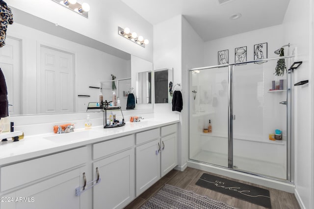 bathroom featuring walk in shower, vanity, and wood-type flooring