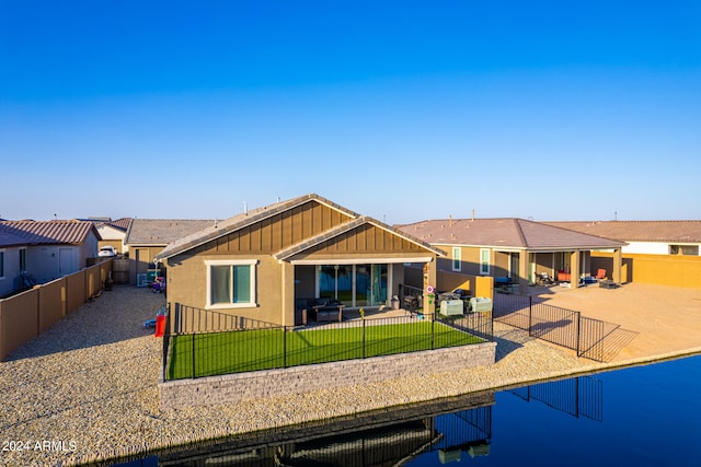 back of house featuring a patio, a water view, and a yard