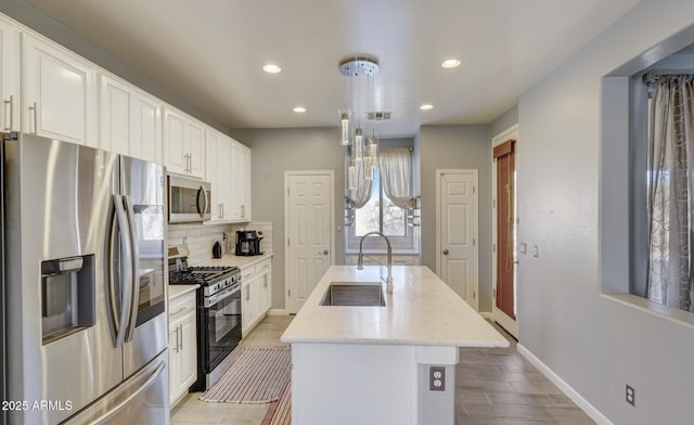 kitchen featuring a center island with sink, white cabinetry, sink, and appliances with stainless steel finishes