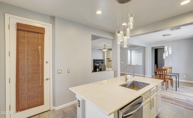 kitchen featuring ceiling fan, sink, dishwasher, hanging light fixtures, and an island with sink