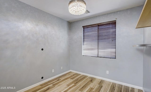 spare room with light hardwood / wood-style flooring and a notable chandelier