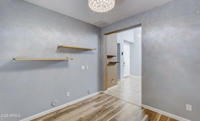 clothes washing area with light wood-type flooring and a notable chandelier