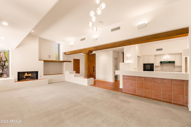 unfurnished living room featuring light colored carpet, high vaulted ceiling, and sink