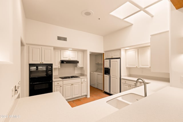 kitchen featuring washer and dryer, sink, a towering ceiling, light tile patterned flooring, and black appliances