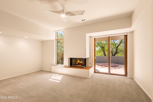 unfurnished living room with carpet, ceiling fan, and a multi sided fireplace