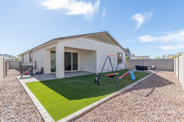 rear view of house with a playground, a lawn, and a patio