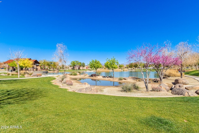 view of pool with a water view and a lawn