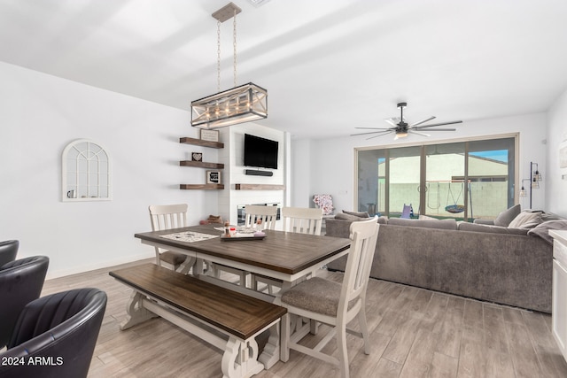 dining space featuring light hardwood / wood-style floors and ceiling fan with notable chandelier