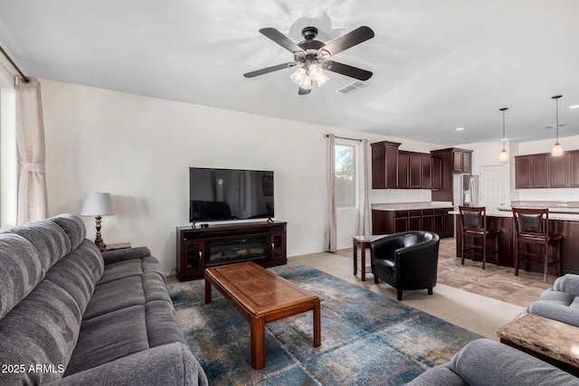 living room with light carpet, visible vents, and a ceiling fan