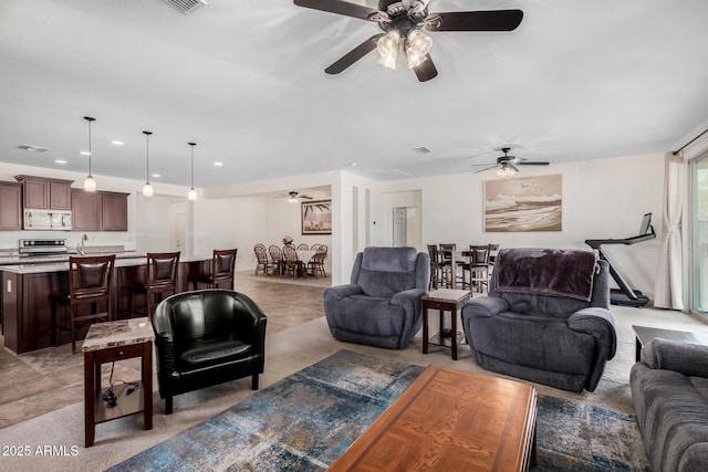 living room featuring a ceiling fan, recessed lighting, light colored carpet, and light tile patterned flooring