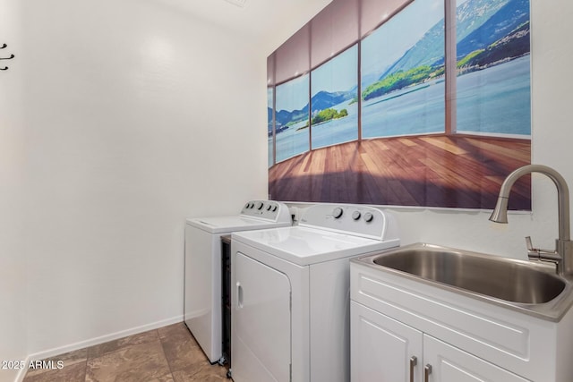 clothes washing area with a sink, washing machine and clothes dryer, cabinet space, and baseboards