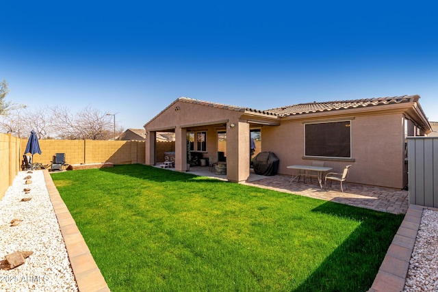 rear view of house with a patio, a yard, a fenced backyard, and stucco siding