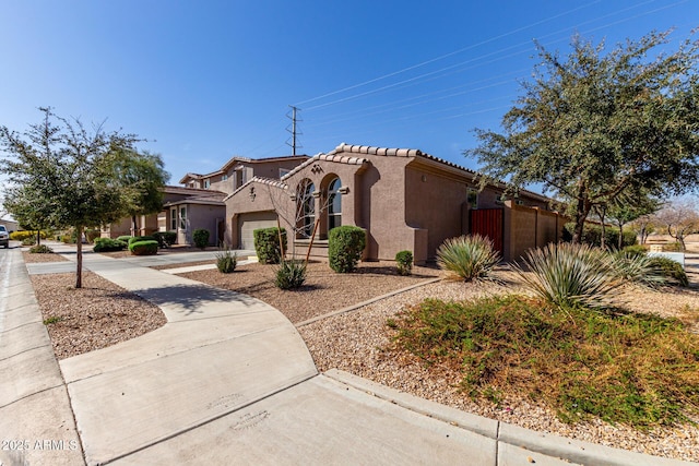 mediterranean / spanish-style house featuring driveway, a tile roof, an attached garage, and stucco siding