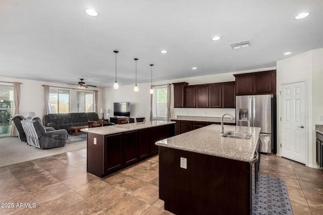 kitchen with open floor plan, visible vents, a sink, and an island with sink