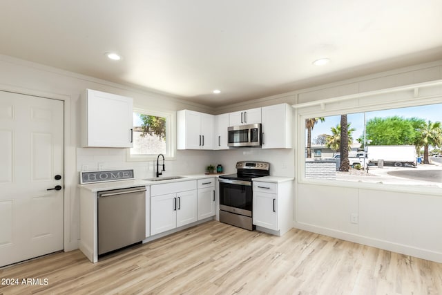 kitchen with sink, appliances with stainless steel finishes, light wood-type flooring, and white cabinets