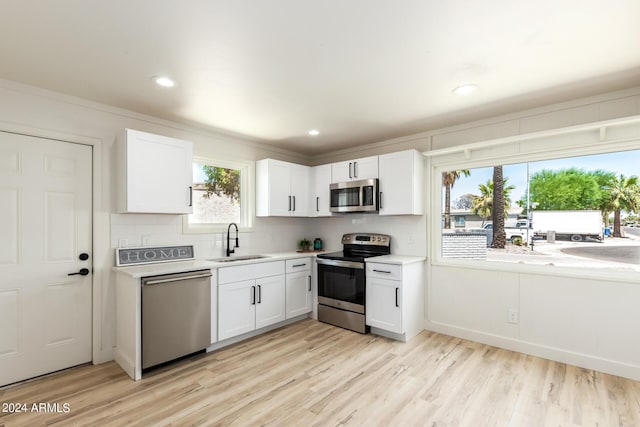 kitchen with sink, stainless steel appliances, light hardwood / wood-style floors, and white cabinets