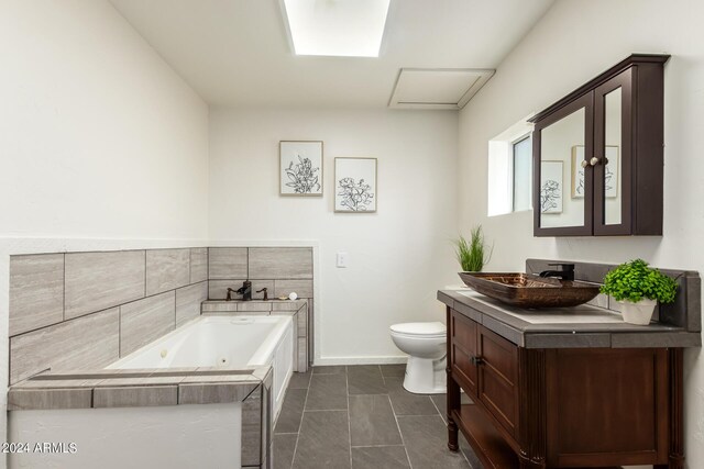 bathroom with a relaxing tiled tub, tile patterned floors, vanity, and toilet