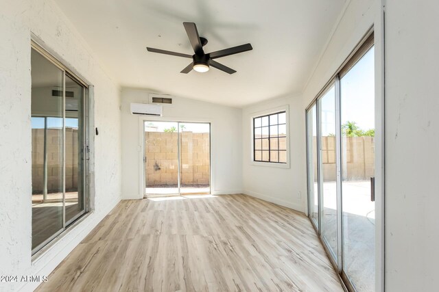 interior space with a wall mounted air conditioner, light hardwood / wood-style flooring, ceiling fan, and vaulted ceiling