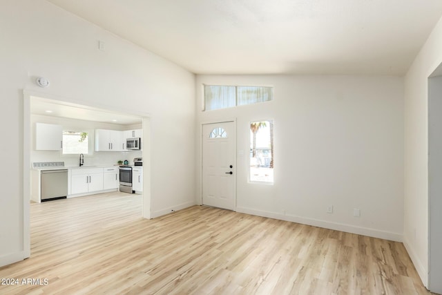 foyer entrance with vaulted ceiling, sink, and light hardwood / wood-style flooring