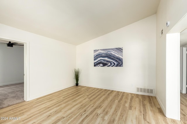 spare room with vaulted ceiling and light hardwood / wood-style flooring