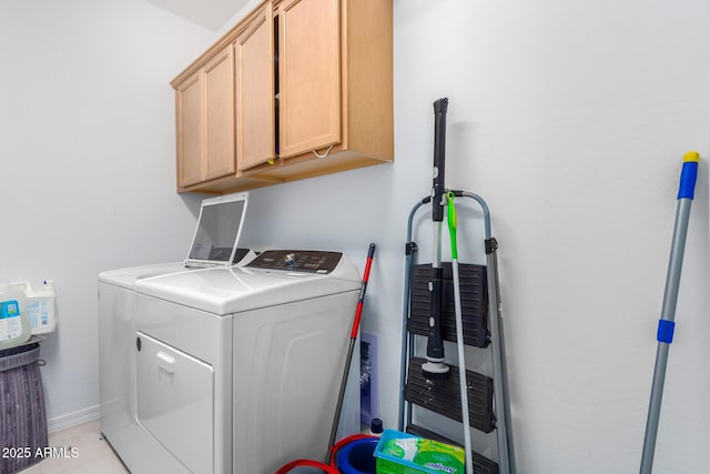 laundry area featuring cabinets, light tile patterned floors, and washer and clothes dryer