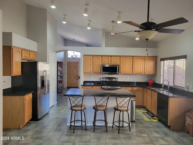 kitchen featuring ceiling fan, appliances with stainless steel finishes, a kitchen island, high vaulted ceiling, and sink