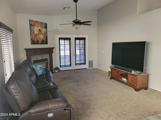 living room featuring french doors, lofted ceiling, a tiled fireplace, ceiling fan, and light carpet