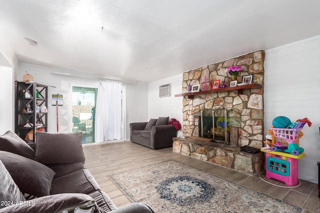 living room featuring a fireplace, hardwood / wood-style flooring, and a wall mounted AC