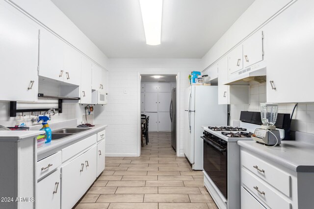 kitchen featuring white cabinets, backsplash, light wood-type flooring, white appliances, and sink