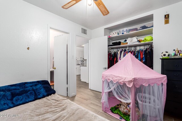 bedroom with light wood-type flooring, ceiling fan, and a closet