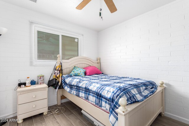 bedroom featuring brick wall, dark wood-type flooring, and ceiling fan