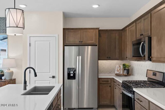9243 E Sector Dr, Mesa, AZ 85212 - kitchen with a sink, decorative light fixtures, decorative backsplash, light countertops, and appliances with stainless steel finishes