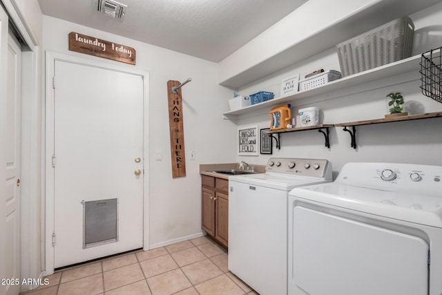 washroom with cabinets, sink, light tile patterned floors, and washing machine and clothes dryer