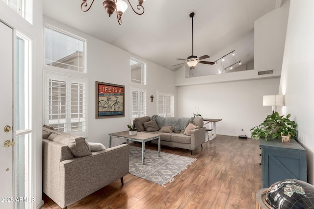 living room featuring wood-type flooring, ceiling fan with notable chandelier, a wealth of natural light, and high vaulted ceiling