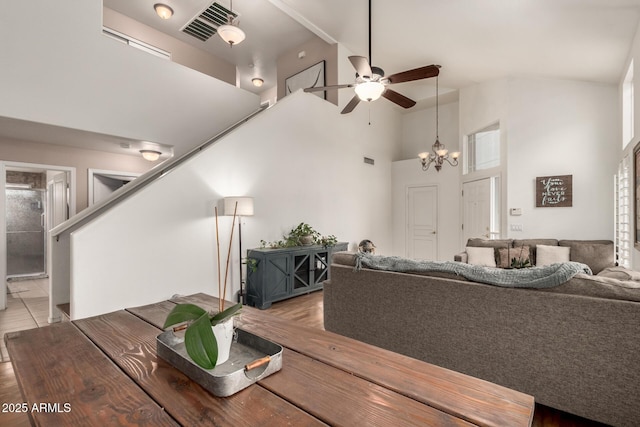 living room with ceiling fan with notable chandelier and high vaulted ceiling