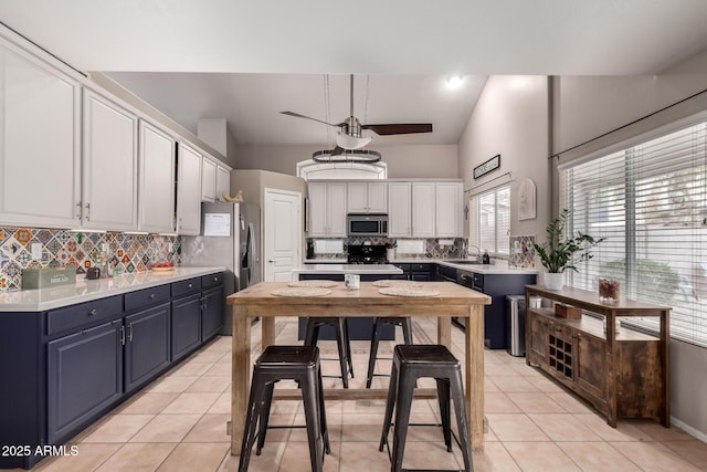 kitchen with blue cabinetry, sink, white cabinetry, light tile patterned floors, and backsplash