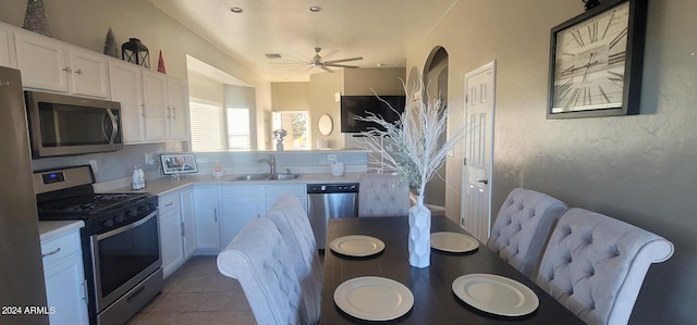 kitchen with white cabinets, sink, ceiling fan, dark tile patterned floors, and stainless steel appliances