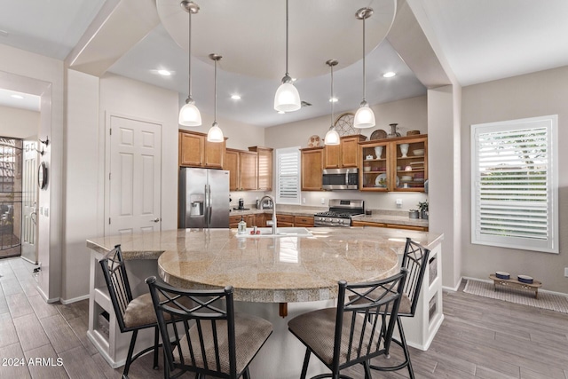 kitchen featuring a breakfast bar, a spacious island, sink, appliances with stainless steel finishes, and wood-type flooring