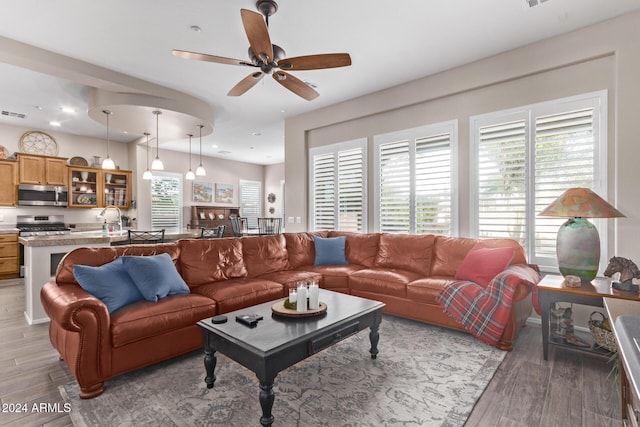 living room featuring ceiling fan, light hardwood / wood-style flooring, and sink