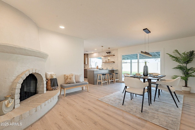 dining room with sink, a stone fireplace, and light hardwood / wood-style floors