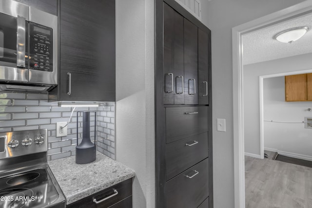 kitchen with light stone countertops, stainless steel appliances, a textured ceiling, light wood-style floors, and backsplash