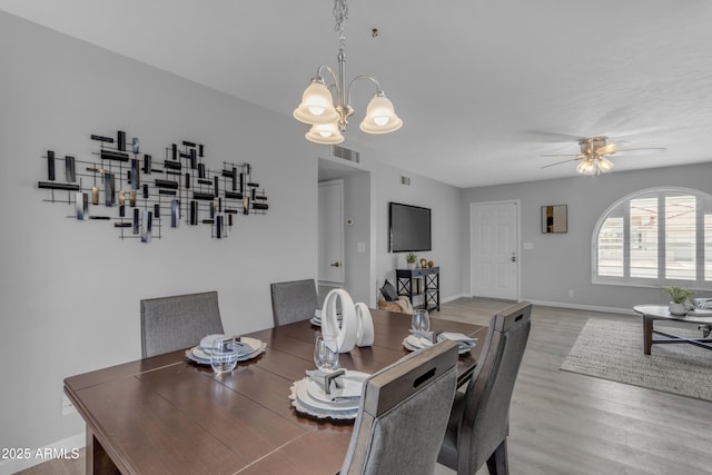 dining area with ceiling fan with notable chandelier, visible vents, baseboards, and wood finished floors