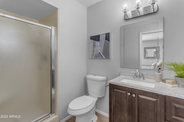 bathroom with vanity, a shower stall, toilet, and baseboards