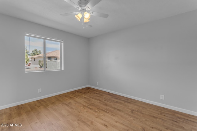 spare room featuring light wood-type flooring, ceiling fan, and baseboards