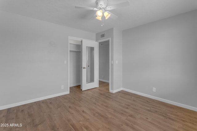 unfurnished bedroom with baseboards, visible vents, a ceiling fan, light wood-style floors, and a closet