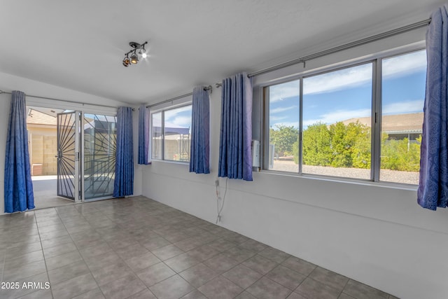 tiled spare room featuring lofted ceiling