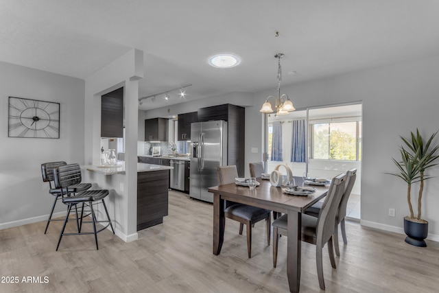 dining room featuring light wood-style floors, baseboards, and a notable chandelier